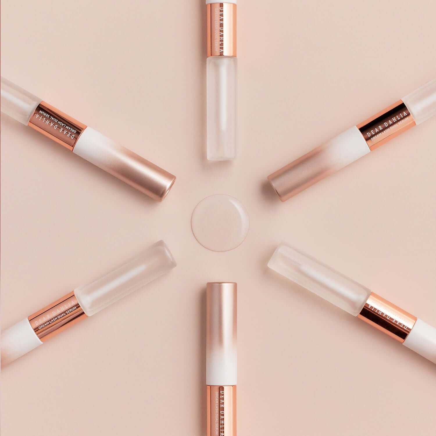 DEAR DAHLIA Dream Lash Dual Serum tubes arranged in a star pattern on a peach background.