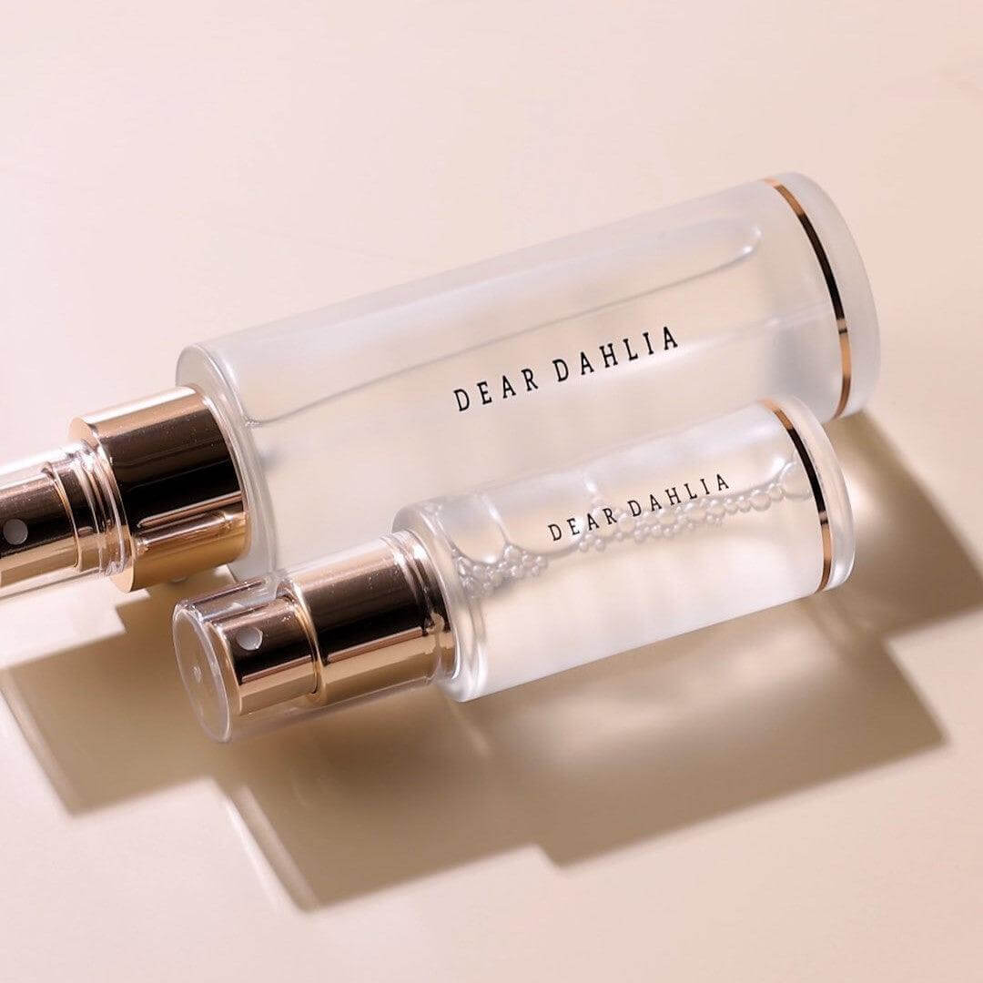 Two bottles of DEAR DAHLIA Endless SKin Setting Spray with elegant gold accents on a neutral background.