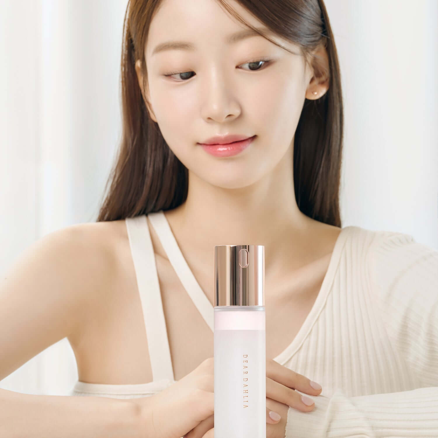 Woman holding DEAR DAHLIA Endless Skin Cream Mist in elegant packaging.