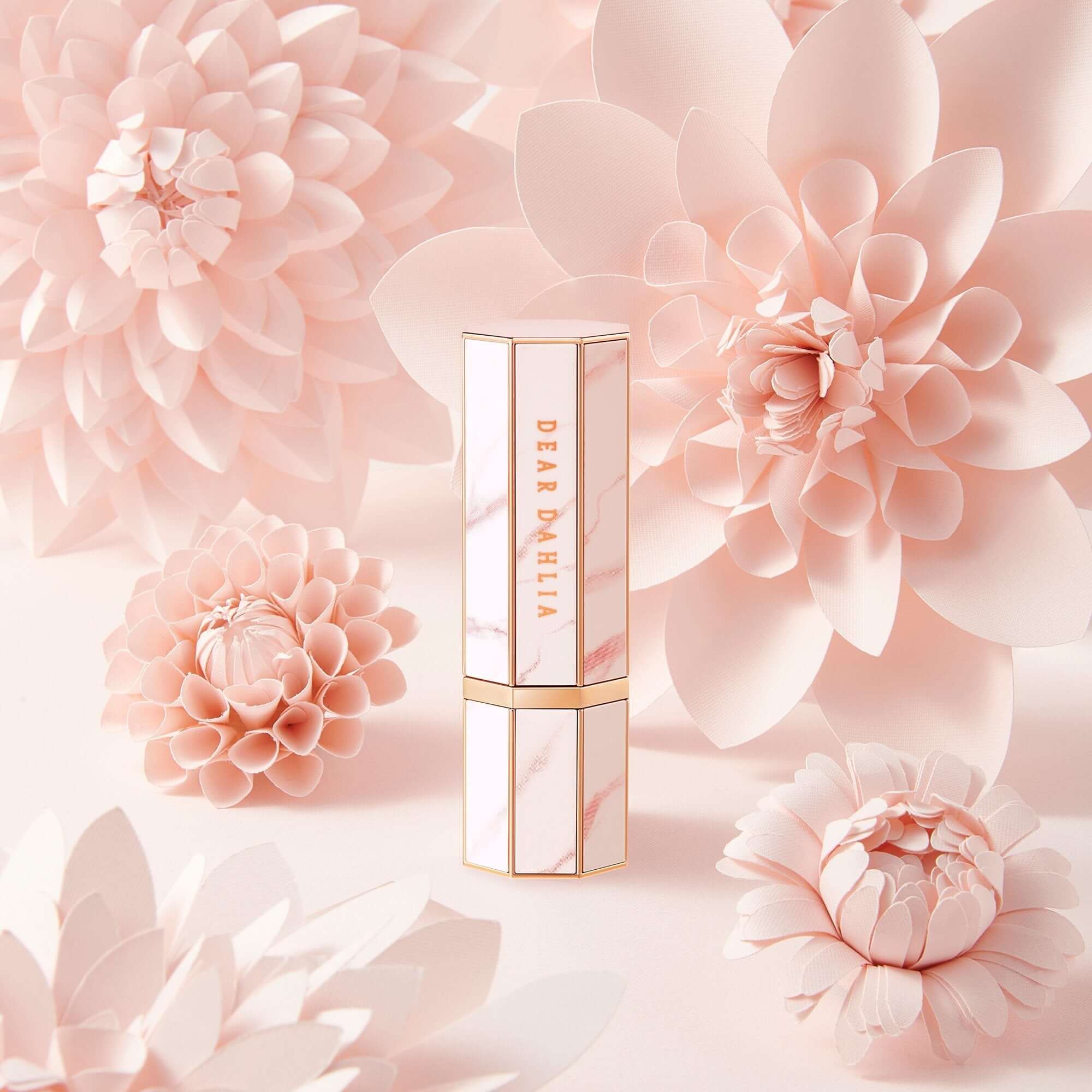 Luxury DEAR DAHLIA Paradise Blooming Night lipstick surrounded by delicate pink dahlia flowers, highlighting elegance and beauty.