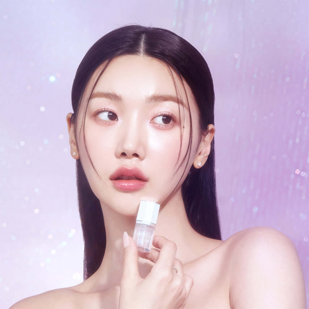 Model showcasing DEAR DAHLIA Paradise Sparkle Lip Glaze against a shimmering background.