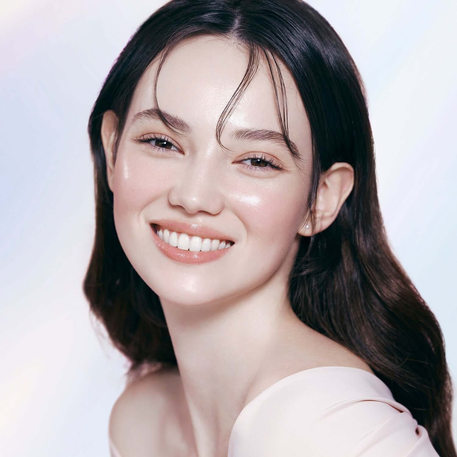 Woman with radiant skin wearing DEAR DAHLIA Prime Layer Glow Primer, showcasing makeup benefits.