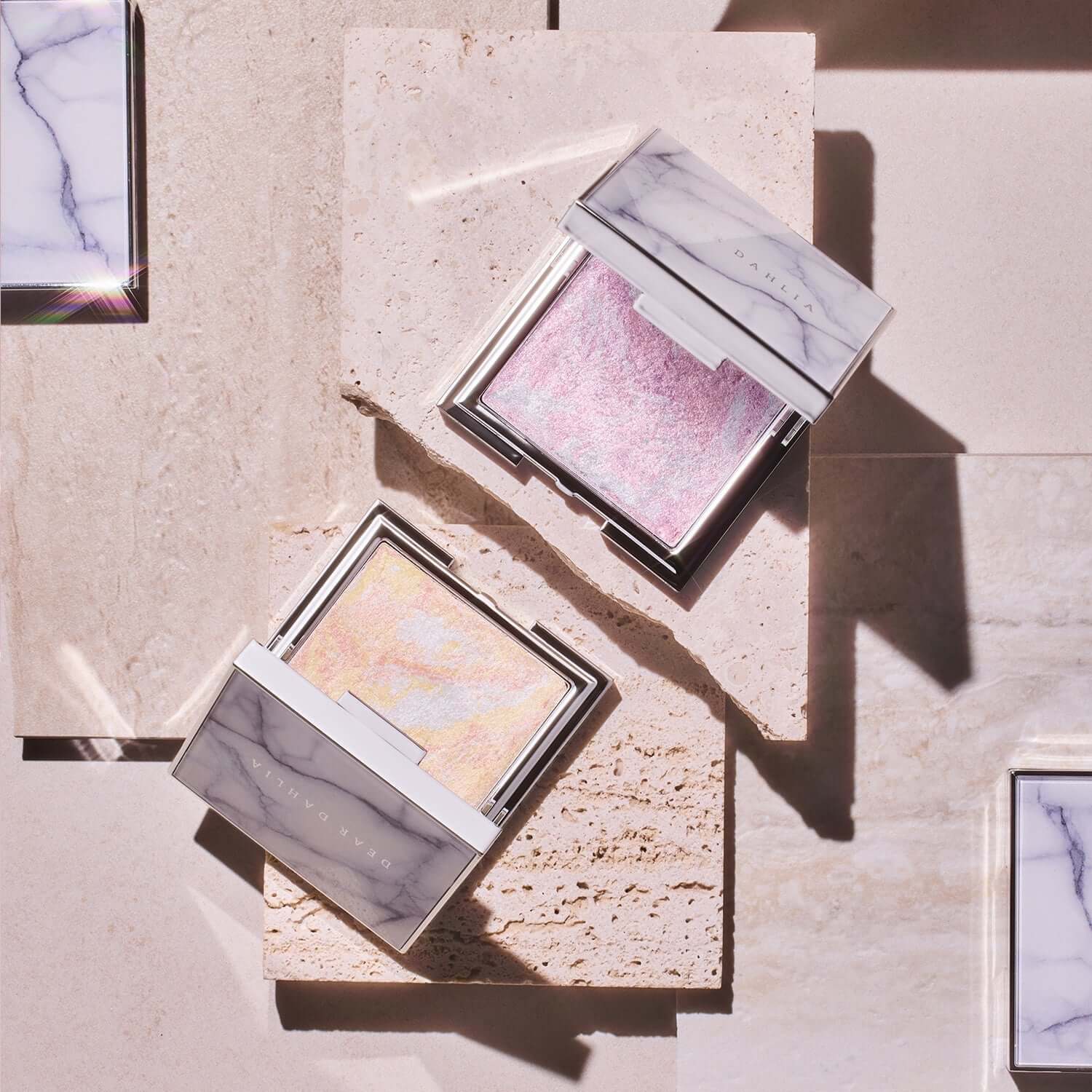 Open DEAR DAHLIA Skin Luminous Highlighter compacts on a beige geometric surface
