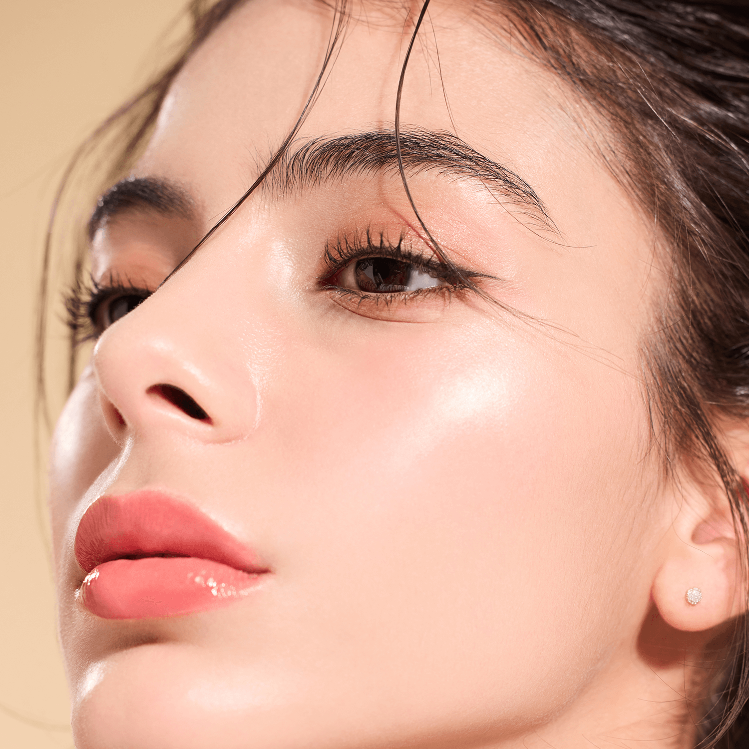 Woman with radiant skin using DEAR DAHLIA Skin Luminous Highlighter for a glowing look.