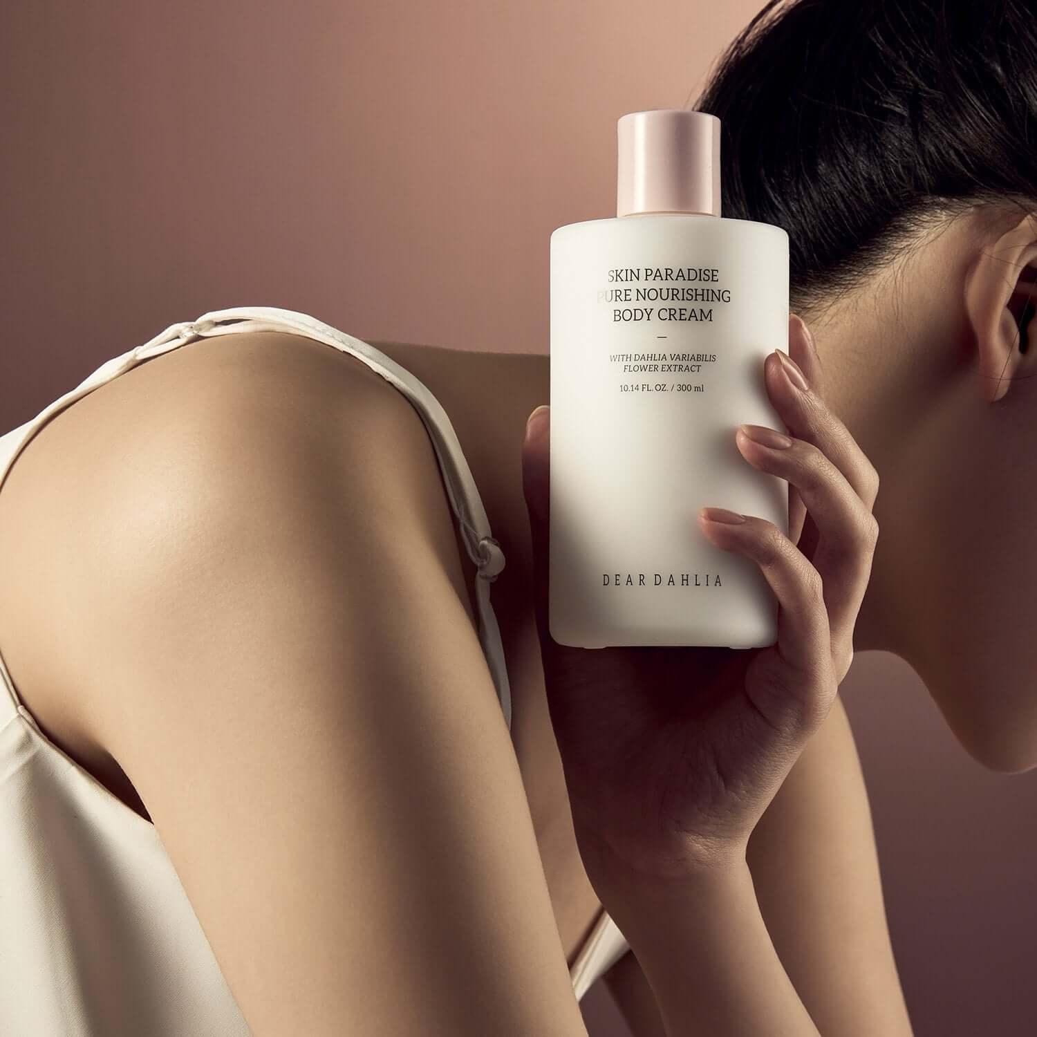 Person holding DEAR DAHLIA Skin Paradise Pure Nourishing Body Cream against a soft background.