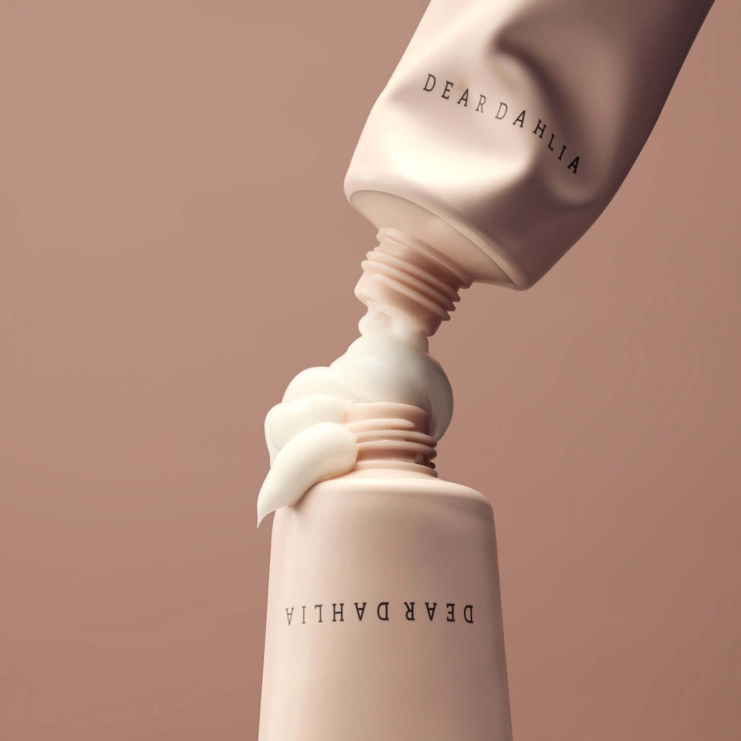 DEAR DAHLIA Skin Paradise Sheer Soft Hand Cream in an elegant beige tube with flowing cream, showcasing luxurious packaging.