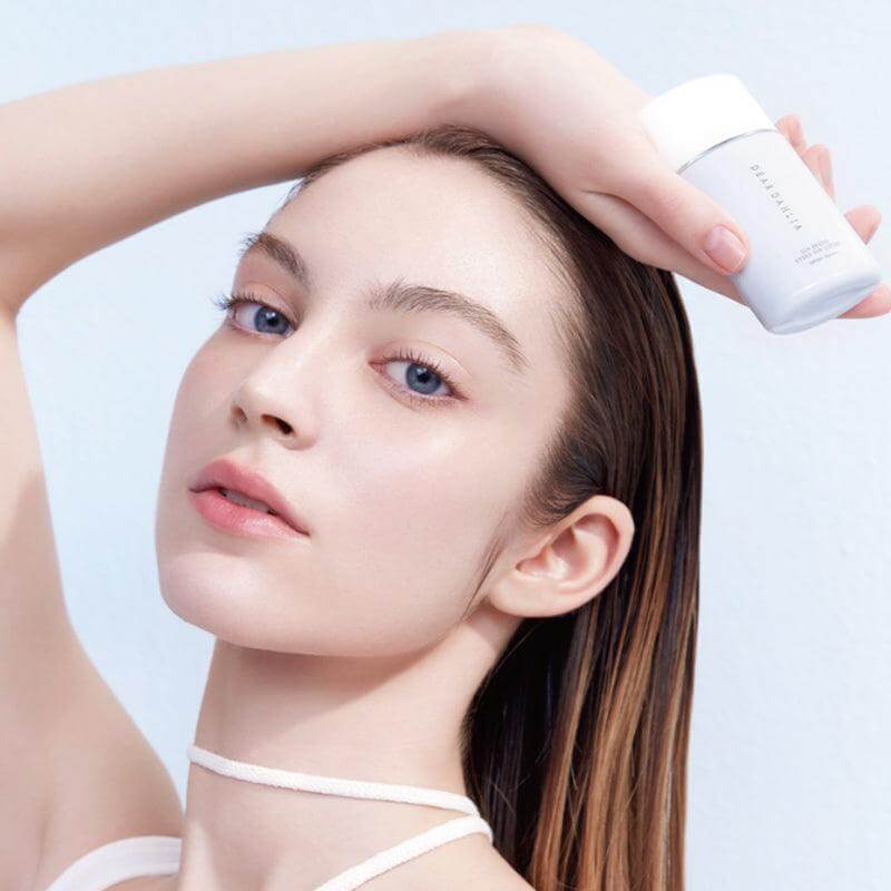 Model holding DEAR DAHLIA Sun Breeze Hydro Sun Lotion, showcasing its packaging and texture.