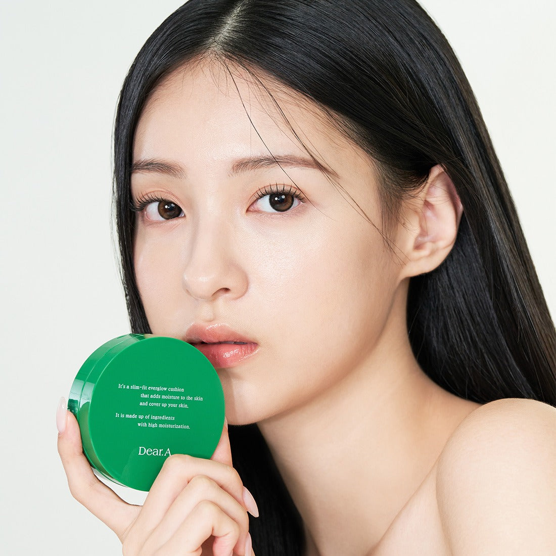 Model holding DEAR.A Slim Fit Everglow Cushion 10g showcasing the product's packaging and use on smooth skin.