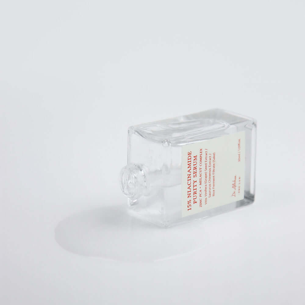 DR.ALTHEA 15% Niacinamide Purity Serum 30ml bottle lying on side with spilled contents on white background