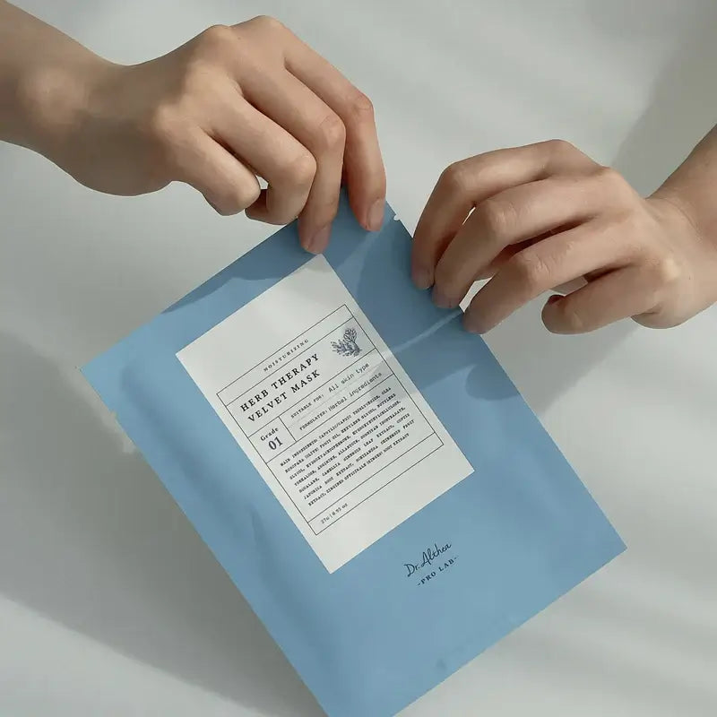 Hands holding DR.ALTHEA Herb Therapy Velvet Mask in light blue packaging for skincare.