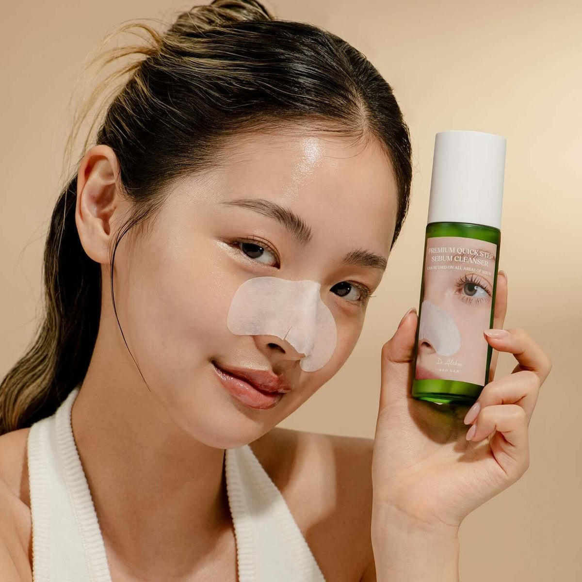 Woman holding DR.ALTHEA Premium Quick Step Sebum Cleanser 100ml with skincare patch on nose