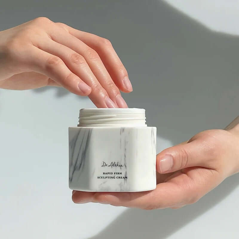 DR.ALTHEA Rapid Firm Sculpting Cream 45ml in hand, showcasing the luxurious skincare product with marble-textured packaging.