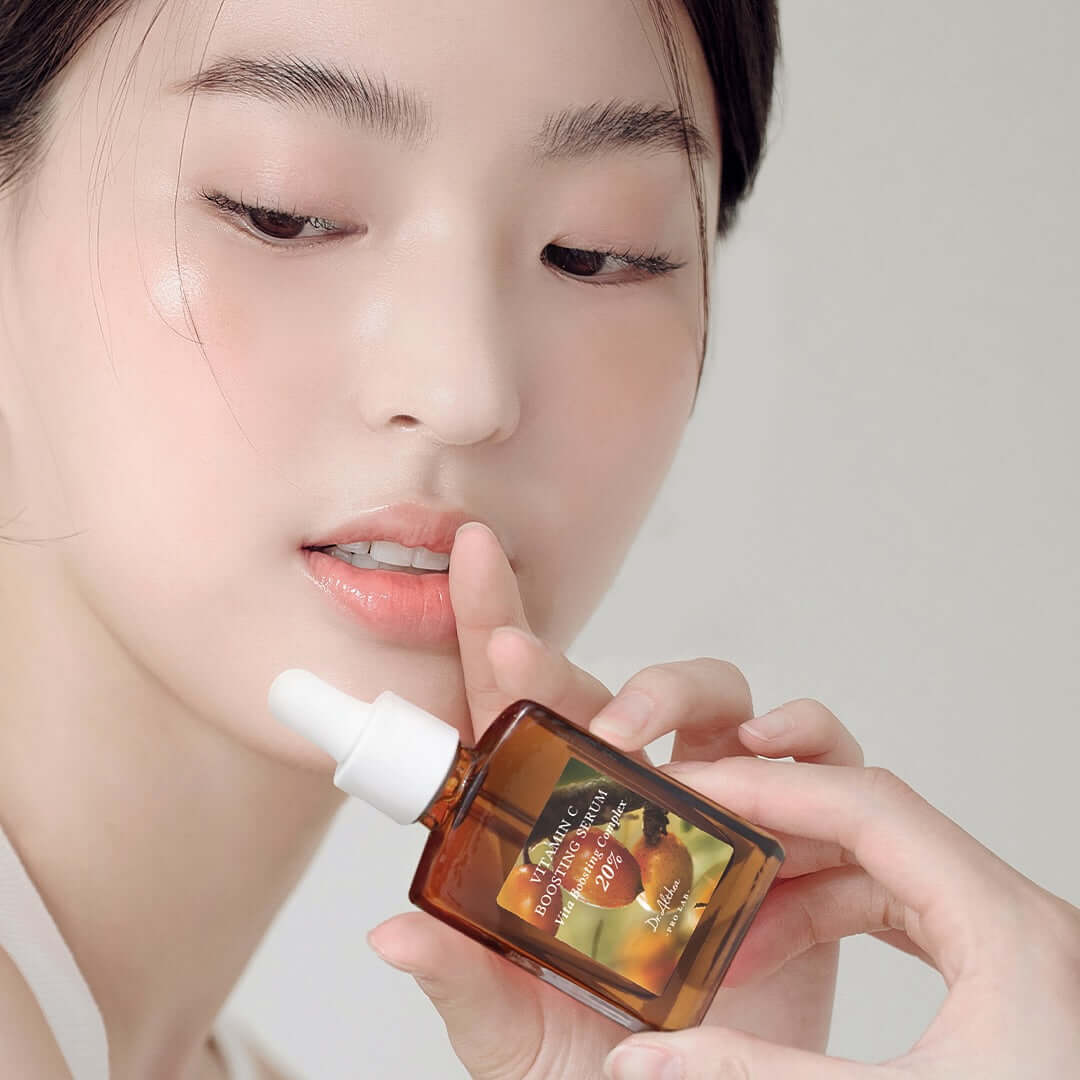 Person holding DR.ALTHEA Vitamin C Boosting Serum 30ml bottle near face.