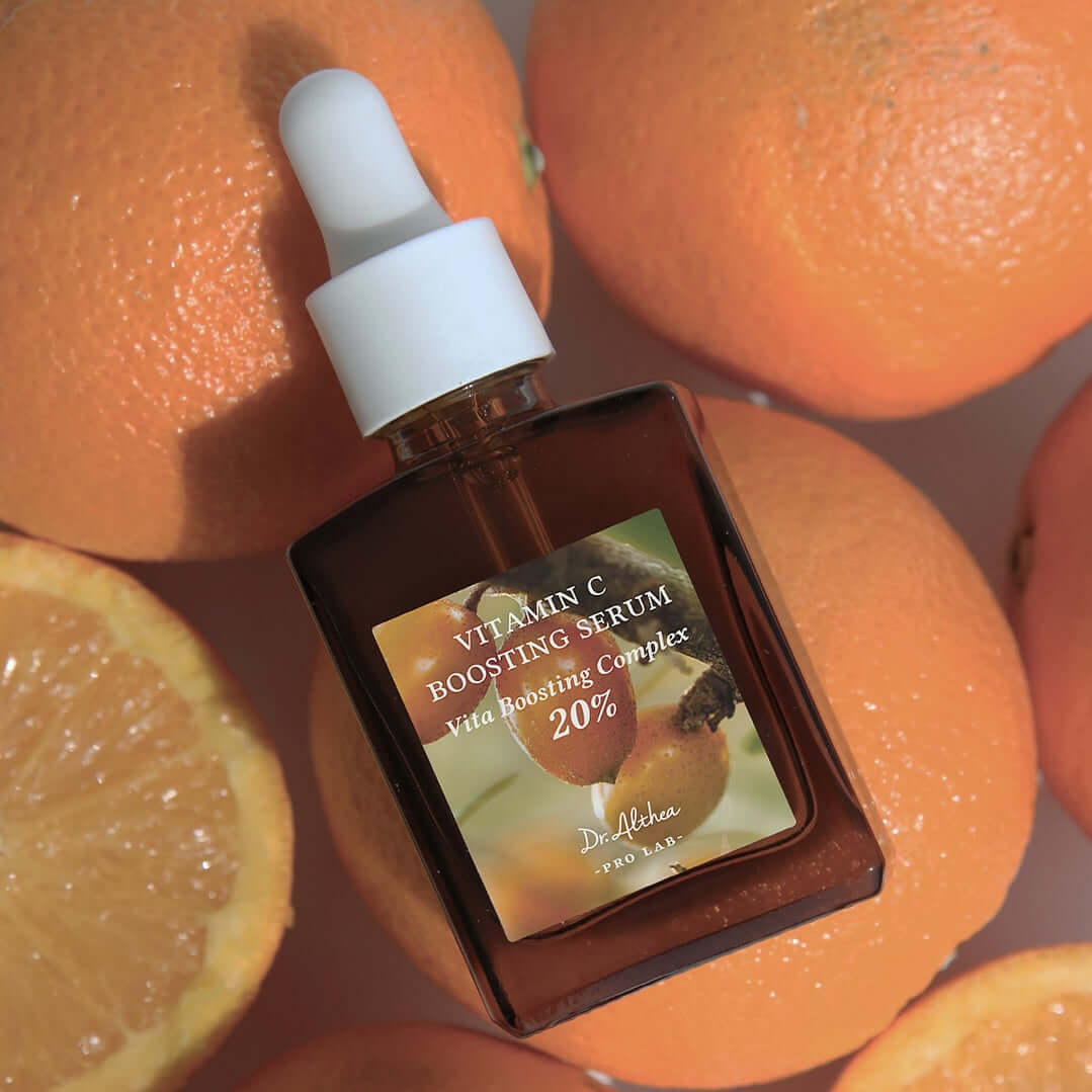 DR.ALTHEA Vitamin C Boosting Serum 30ml with dropper surrounded by fresh oranges, highlighting citrus ingredients for radiant skin.