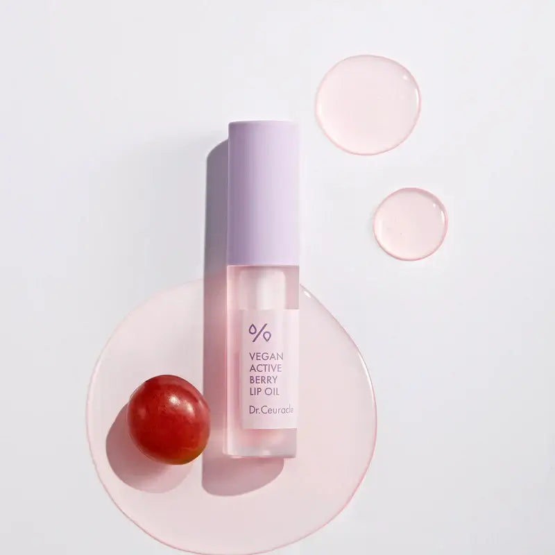 DR.CEURACLE Vegan Active Berry Lip Oil with grape and oil droplets on a white background