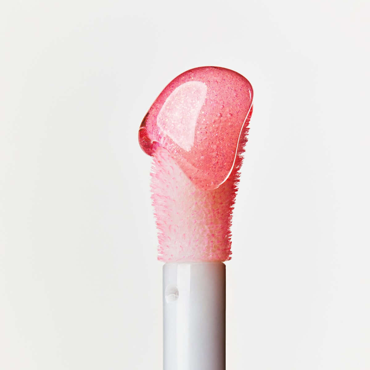 Close-up of ESPOIR Plumpies lip gloss applicator with pink gloss.