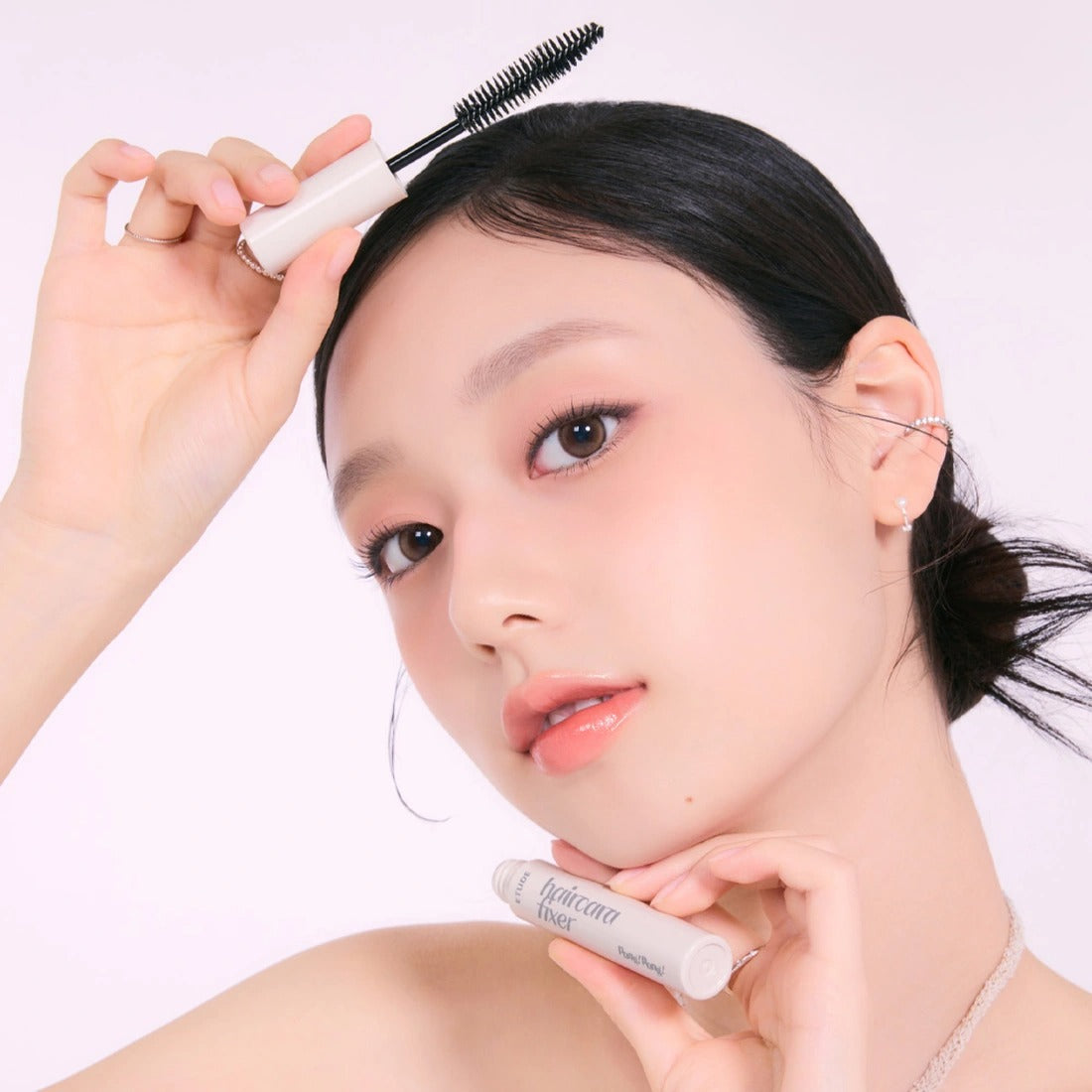 Woman applying ETUDE Pangpang Hair Cara Fixer 10ml with brush applicator for hair styling