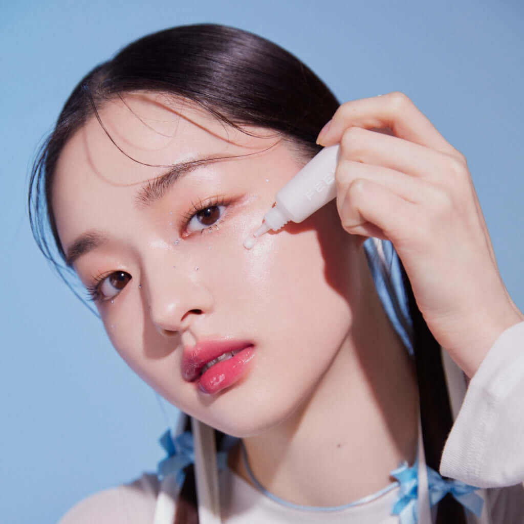 Woman applying FEEV Hyper-Fit Shimmering Serum on her cheek for radiant skin enhancement