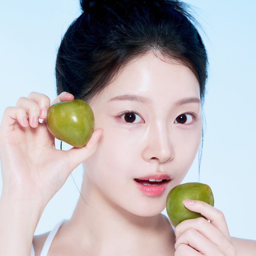 Woman holding green plums, promoting skincare with natural ingredients