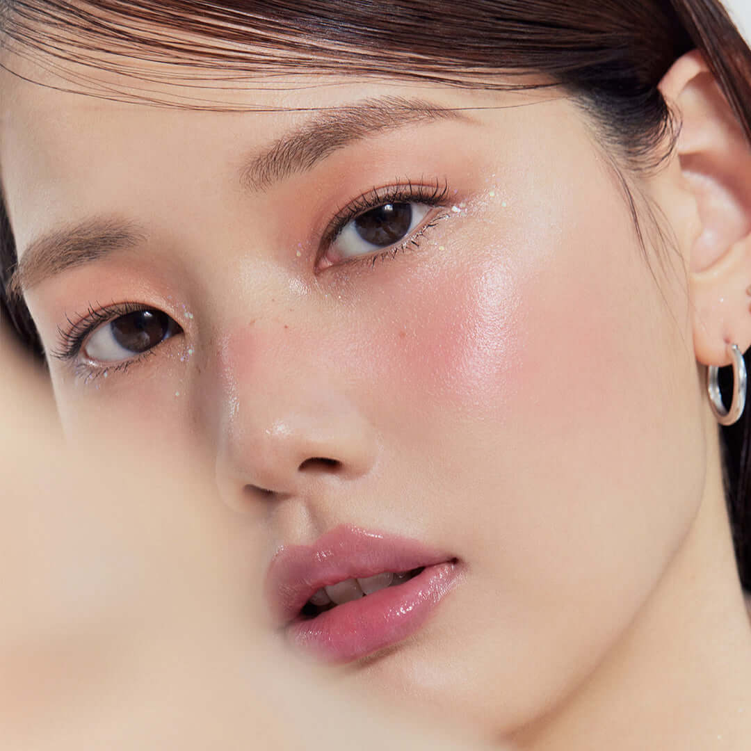 Model wearing makeup with glowing skin effect from GLINT Stick Highlighter