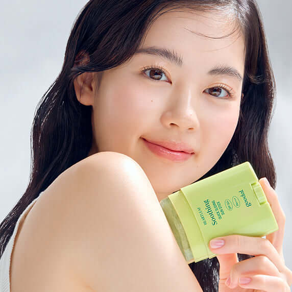 Person holding GOODAL Eoseongcho Calming Quick Sliding Sun Stick, showcasing skincare product for a glowing complexion.