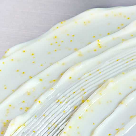 Close-up texture of GOODAL Green Tangerine Vita C Spot Care Cream Alpha 75ml with visible yellow citrus specks on a smooth surface.