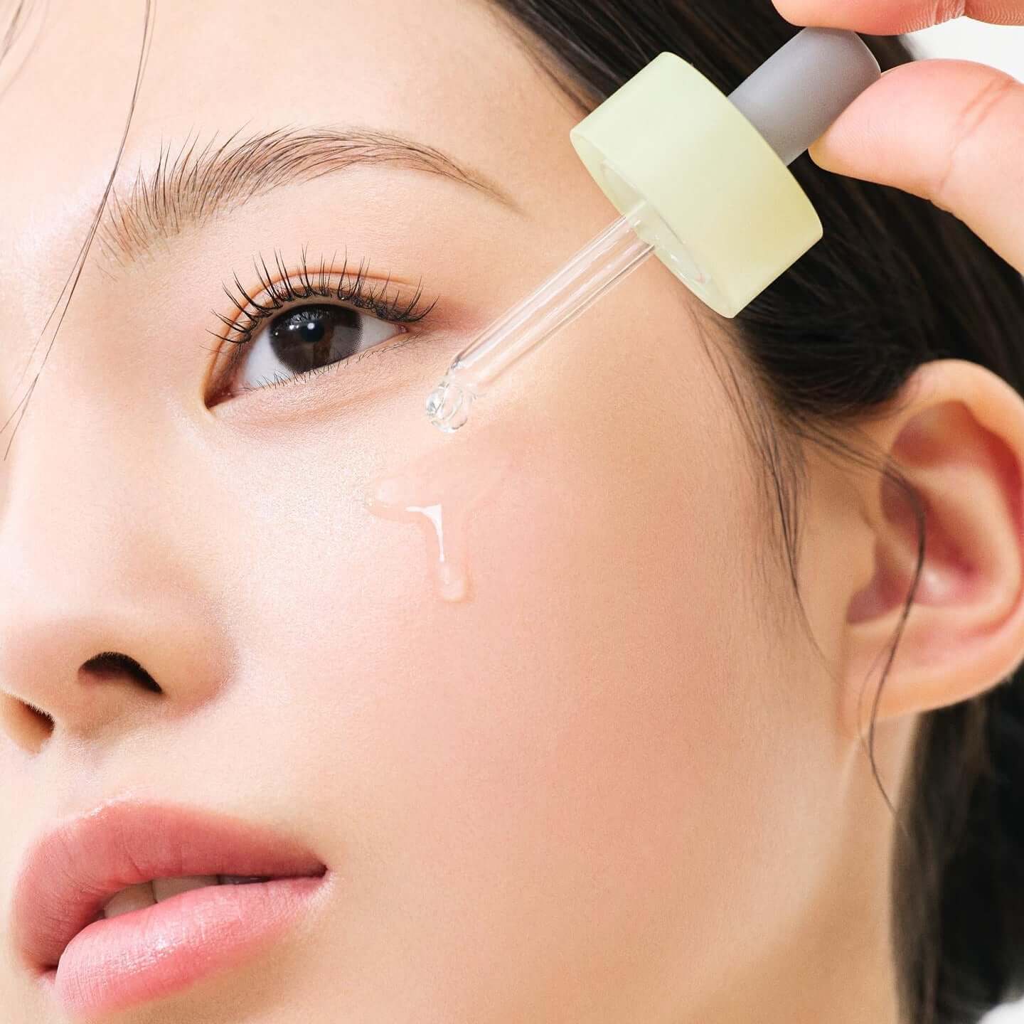 Close-up of woman applying HANYUL Bodunhaengip Pore Fir Serum on face with dropper for skincare.