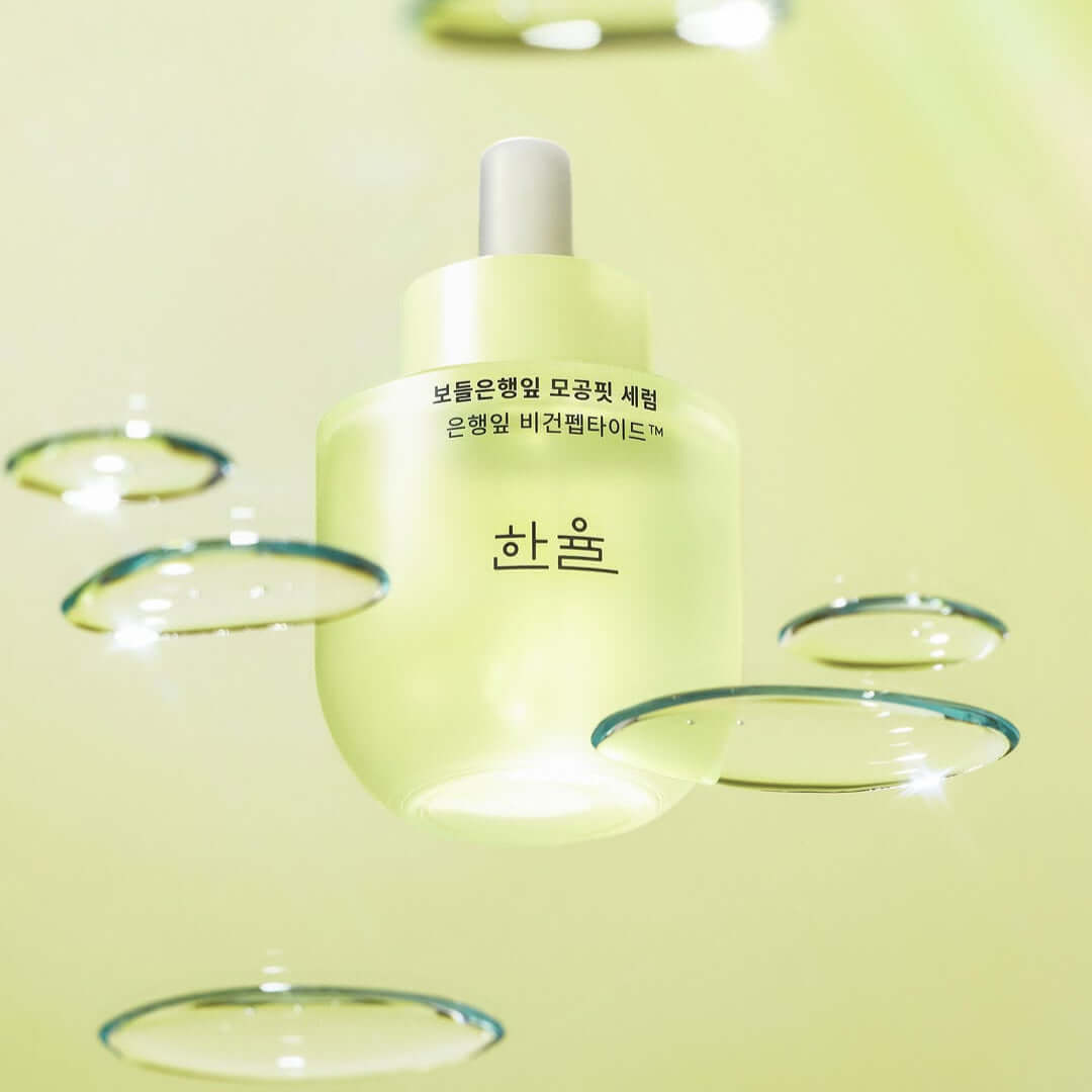 HANYUL Bodunhaengip Pore Fir Serum bottle with fresh glistening droplets on a light green background, showcasing skincare product elegance.