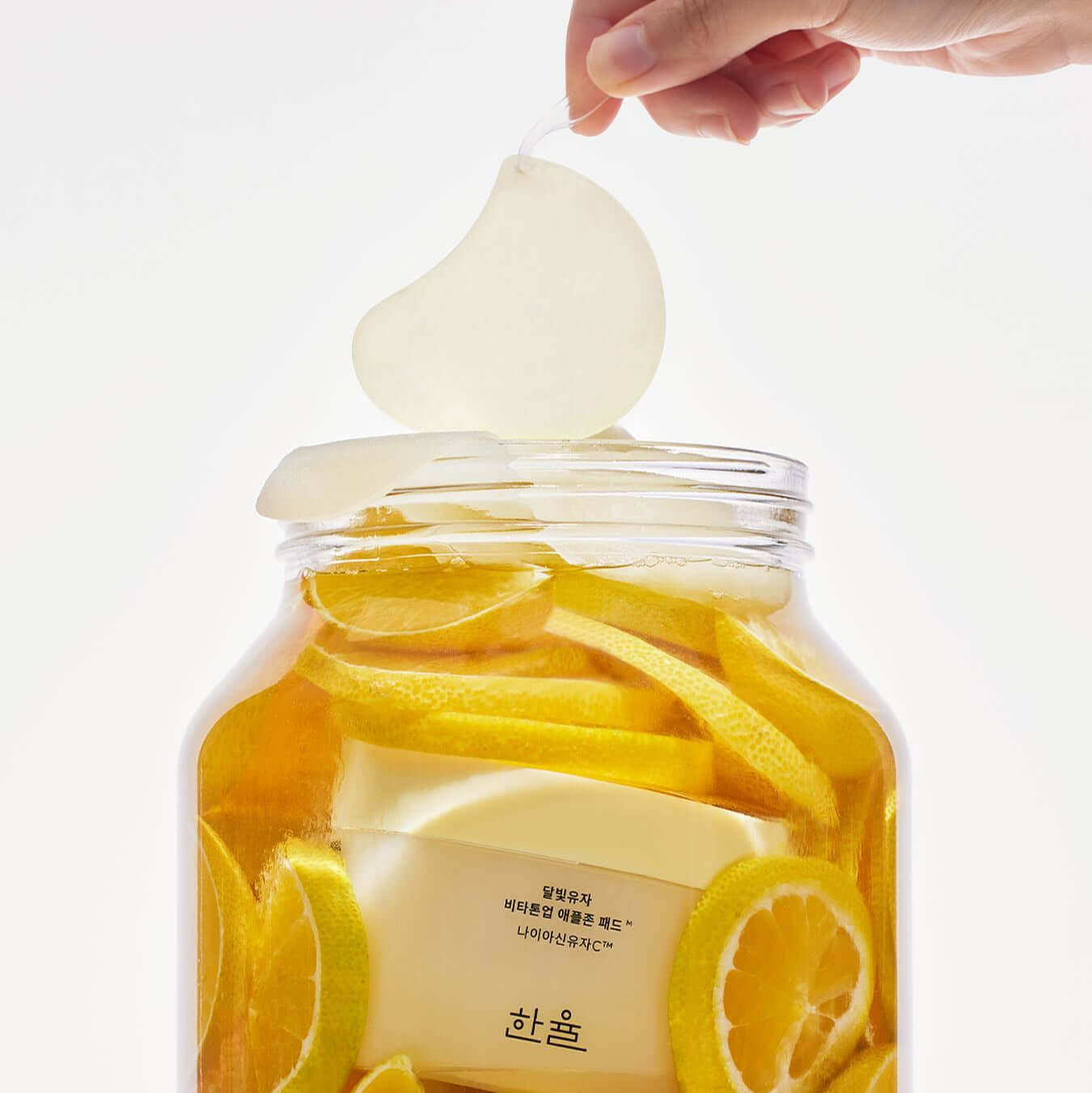 HANYUL Moonlight Yuja Vita Tone Up Apple Zone Pad with citrus slices in a jar, enhancing skin tone and radiance.