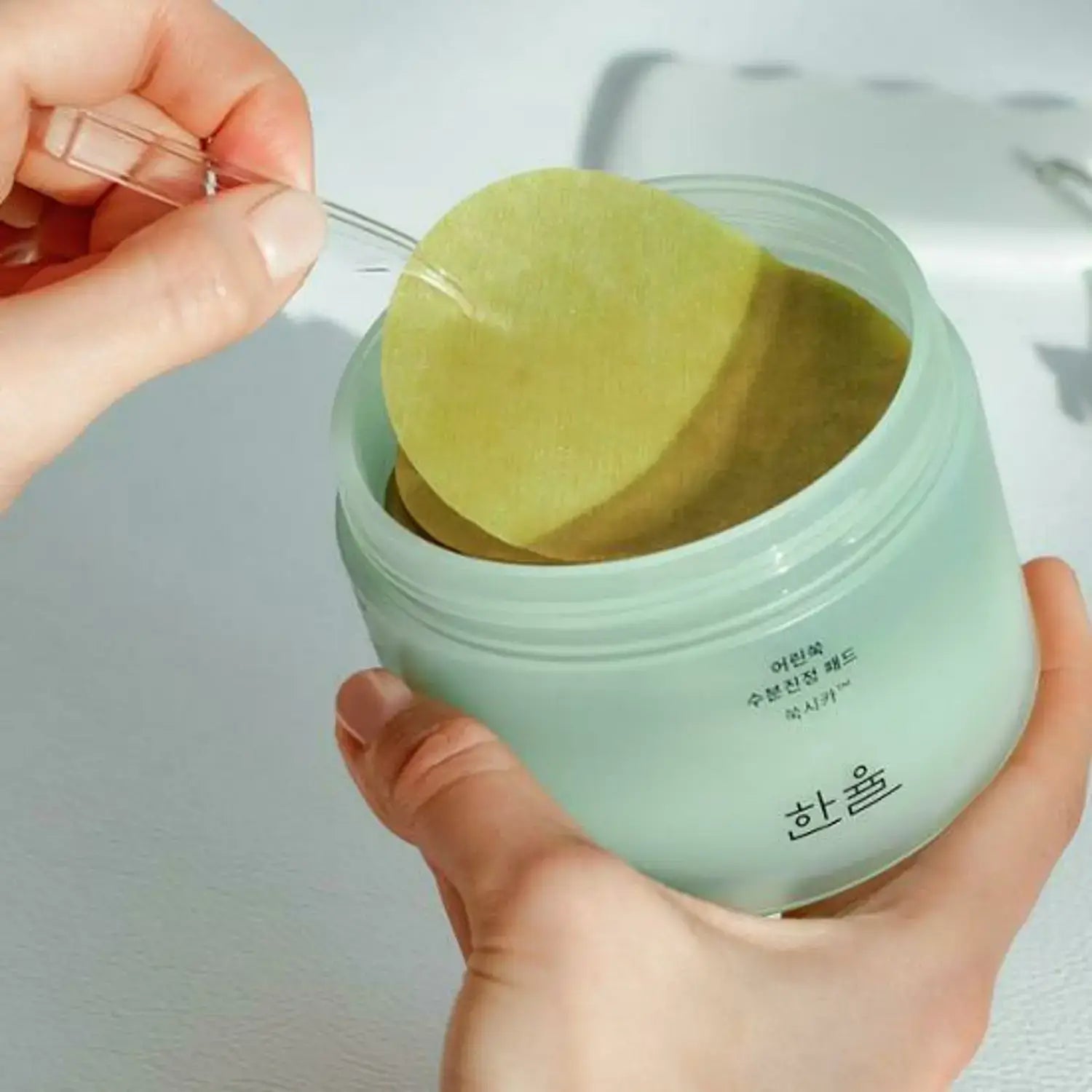 HANYUL Young Mugwort Moisturizing Soohting Pad being removed from green container for skincare use