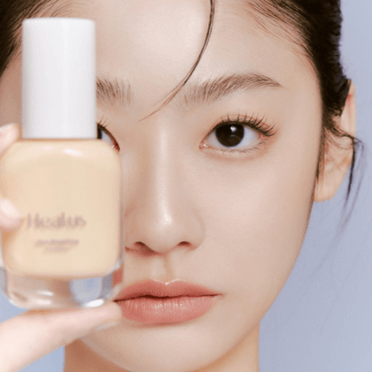 Person holding a bottle of HEALUS Breath Foundation Glow SPF 35 PA++ close to their face