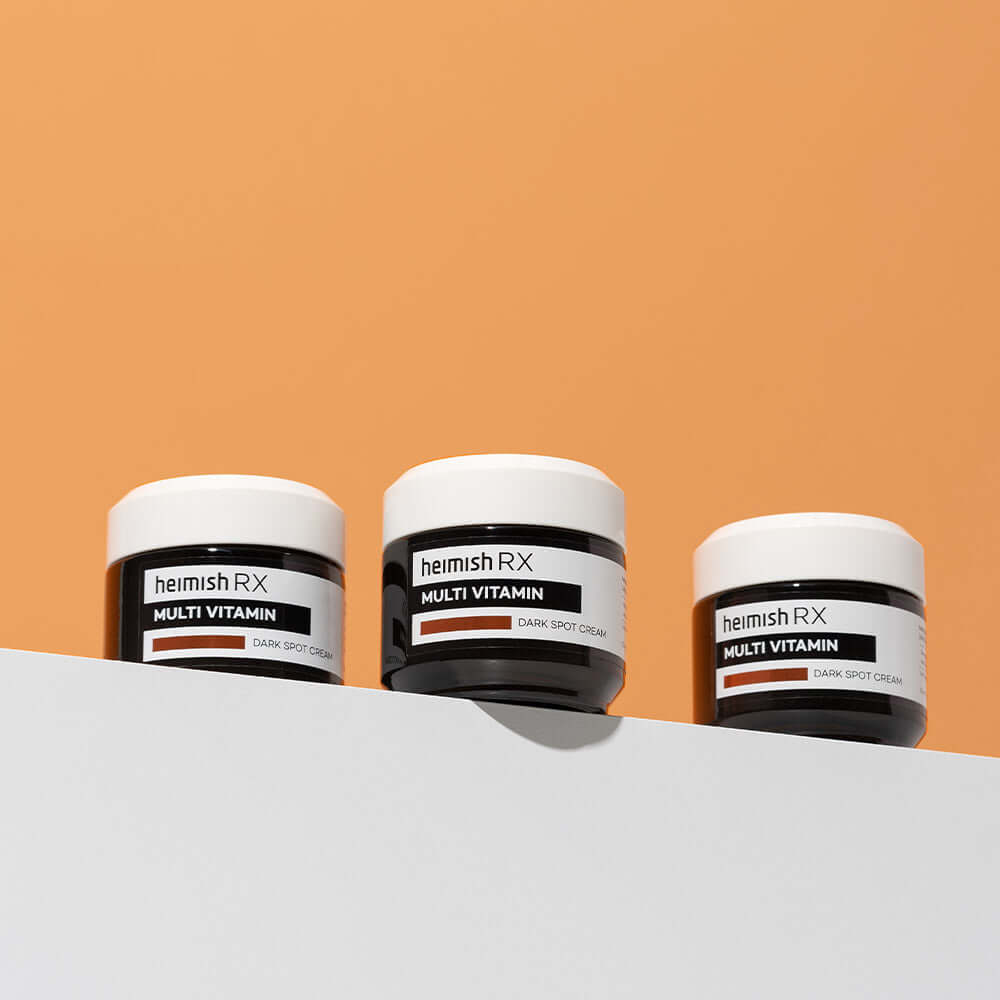 HEIMISH RX Multi Vitamin Dark Spot Cream 50ml on display against orange background.