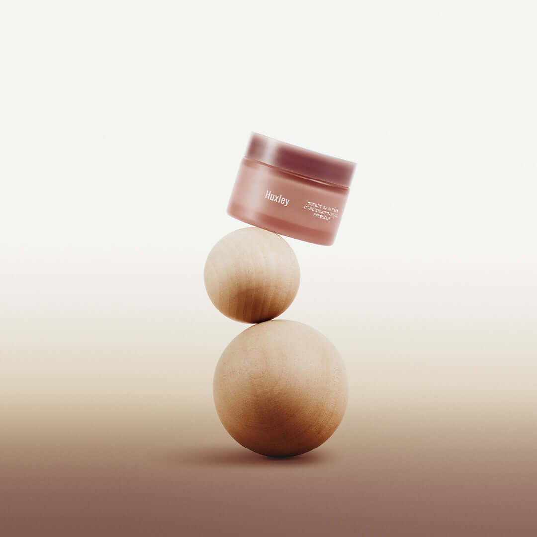 HUXLEY Conditioning Cream Preshape jar artfully balanced on wooden spheres for skincare promotion.
