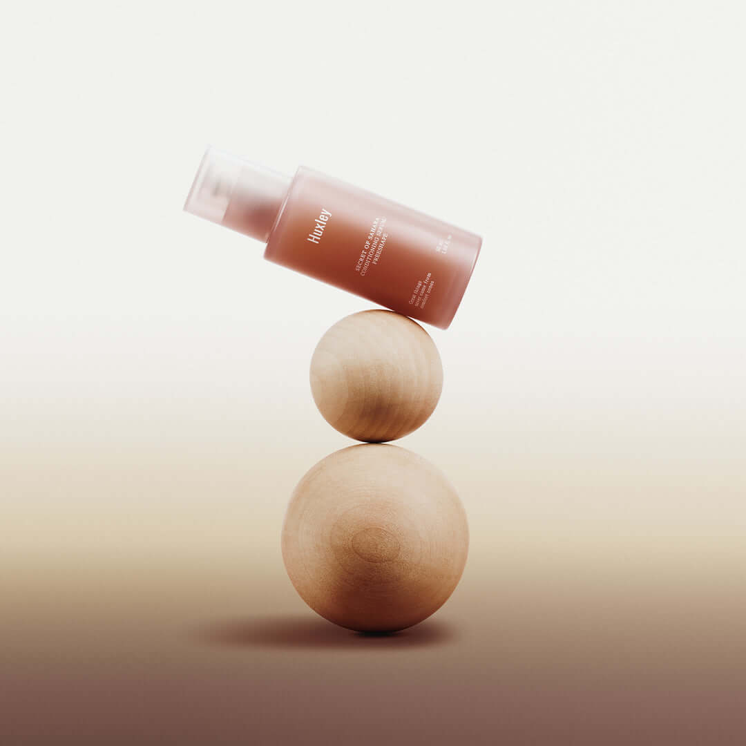 HUXLEY Conditioning Serum Preshape bottle balancing on wooden spheres