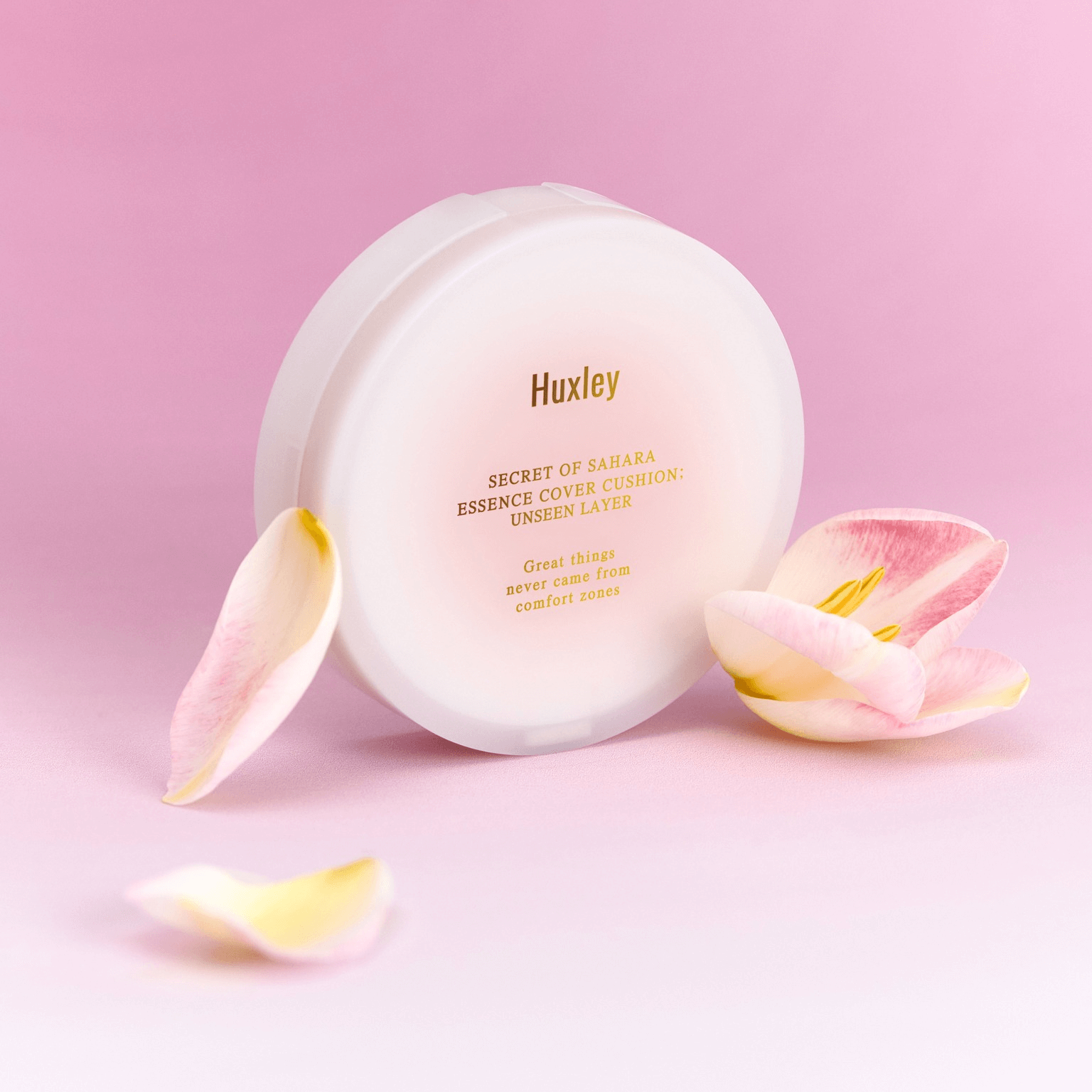 HUXLEY Essence Cover Cushion Unseen Layer displayed with floral petals on a pink background for skincare and beauty care.
