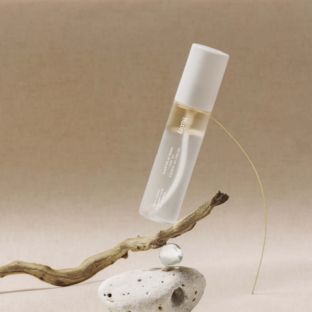 HUXLEY Oil Mist Sense Of Balance product image with elegant minimalistic background, showcasing the sleek bottle design on a beige surface.