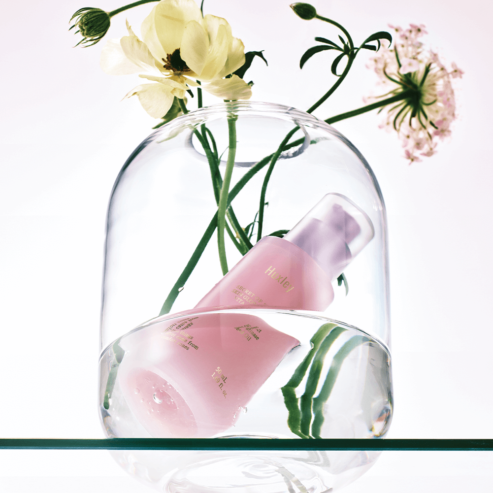 HUXLEY Skin Glow Essence Vita Radiance bottle with flowers under glass dome