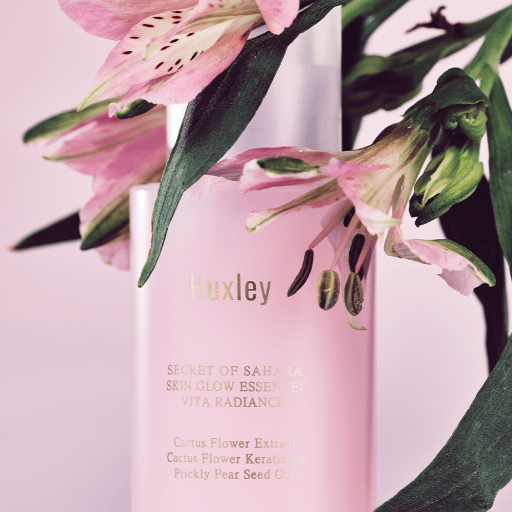 HUXLEY Skin Glow Essence Vita Radiance bottle with floral accents, highlighting the essence's radiance and vitality benefits.