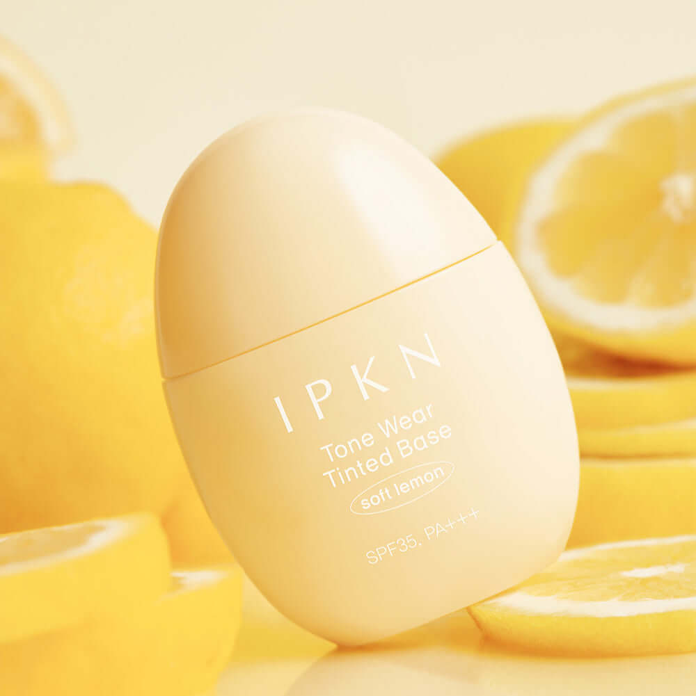 IPKN Tone Wear Tinted Base in soft lemon shade, surrounded by fresh lemons, SPF35 PA+++