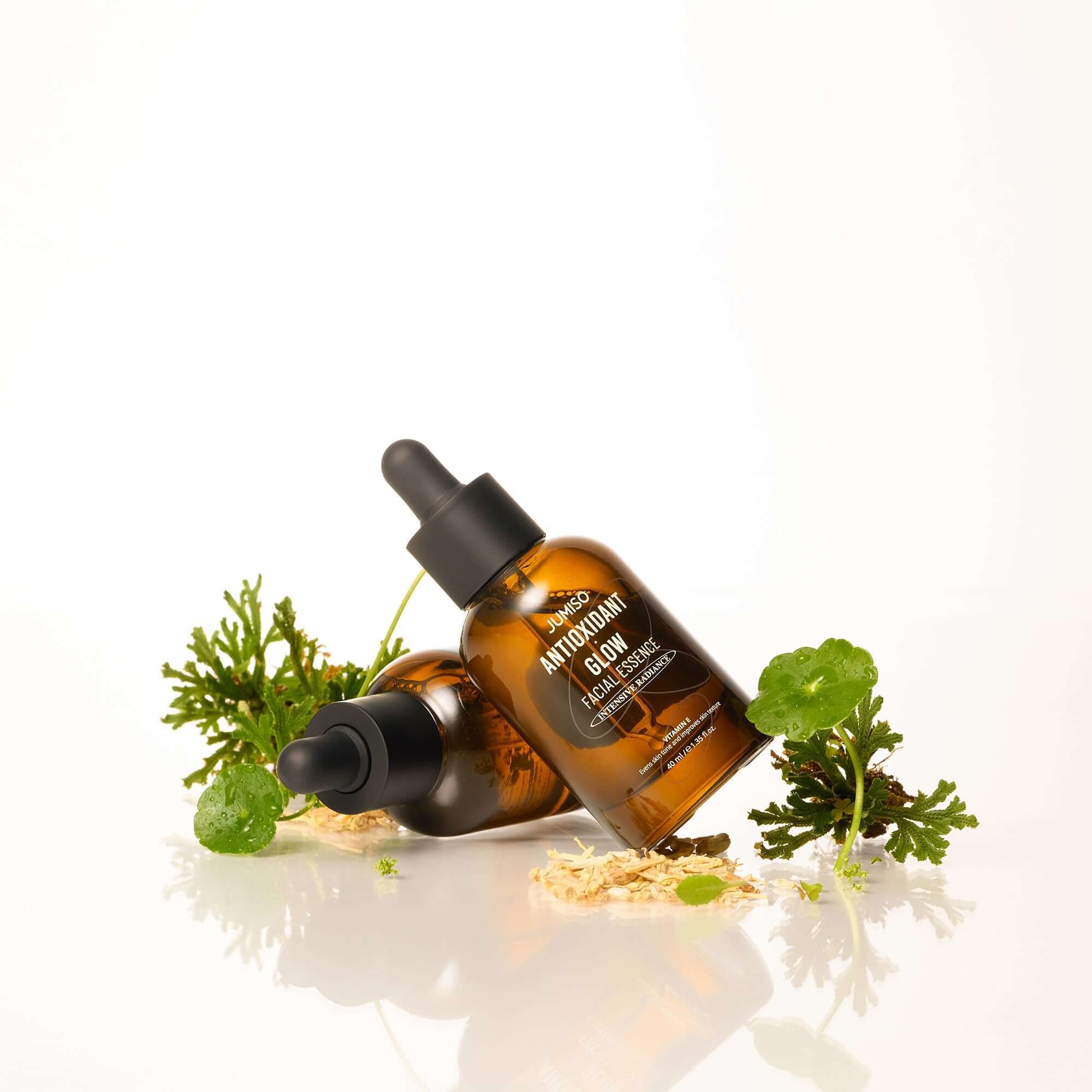 JUMISO Antioxidant Glow Facial Essence bottles with plants for skincare.