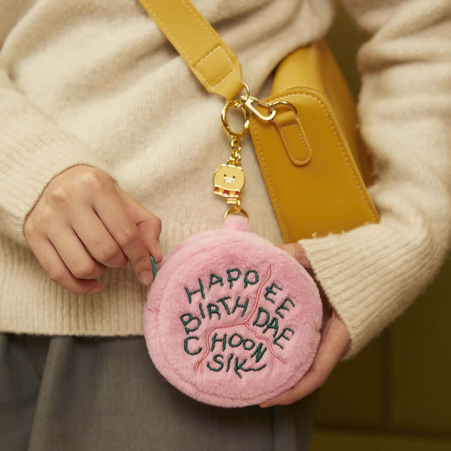 Woman holding KAKAO FRIENDS Mini Pouch Choonsik #HarryPotterCollection in pink with 'HAPPEE BIRTHDAE CHOONSIK' embroidered, attached to yellow bag.