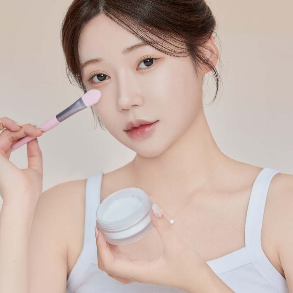 Woman applying KEEP IN TOUCH Mini Pore Eraser Powder with a brush for smooth skin
