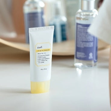 Image of KLAIRS All Day Airy Sunscreen 50g tube on a table with skincare products in the background.