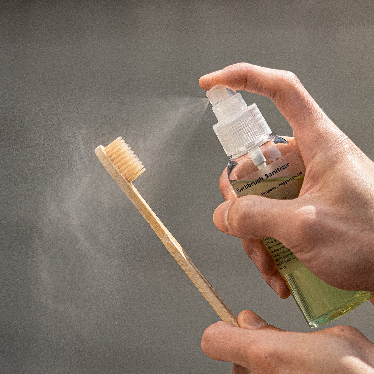 LAZY SOCIETY Toothbrush Sanitizer 100ml spray being applied to a bamboo toothbrush by Gentleman Korea for men’s oral care