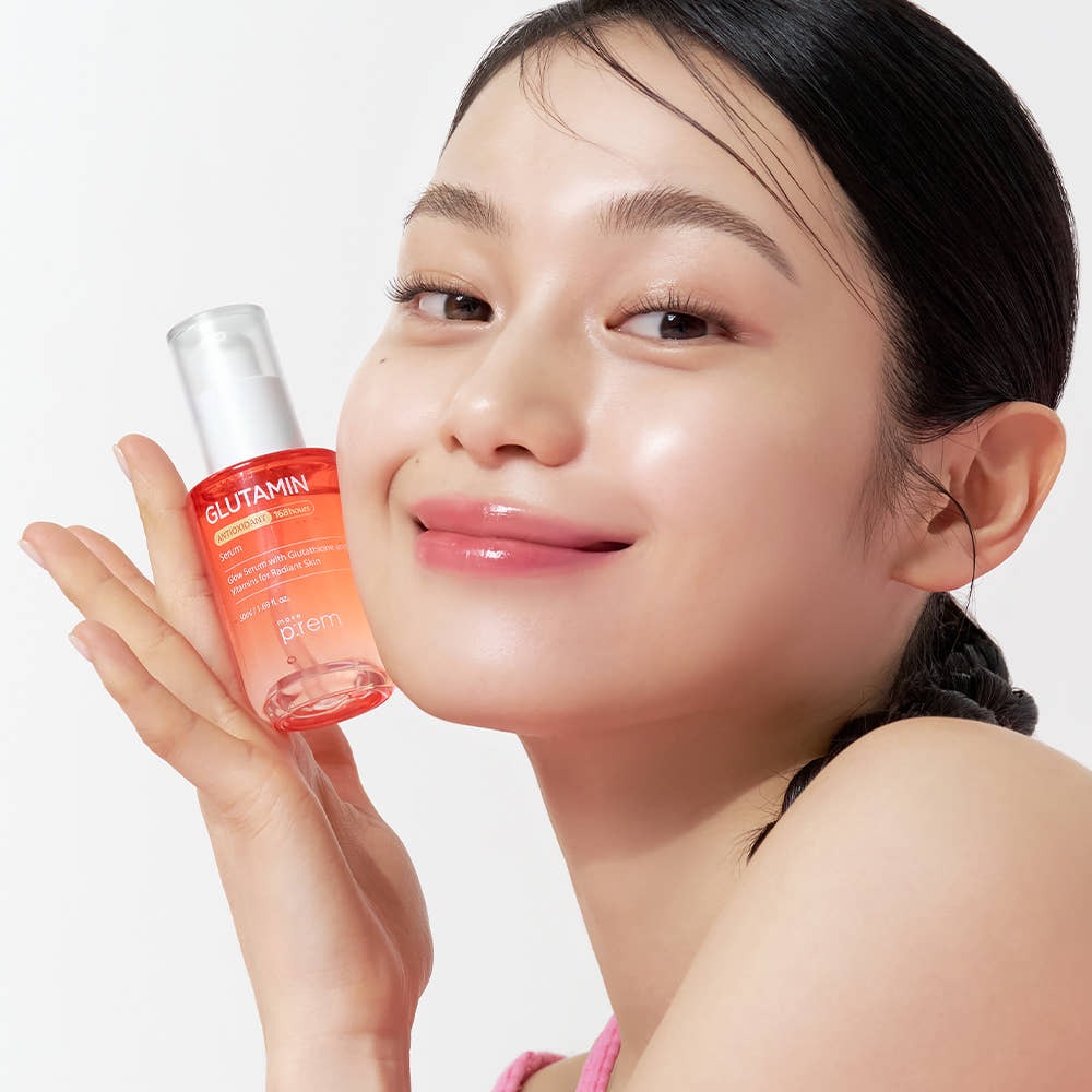 Woman holding MAKE P:REM Glutamine Antioxidant Radiance Serum 50ml bottle, showcasing skincare radiance