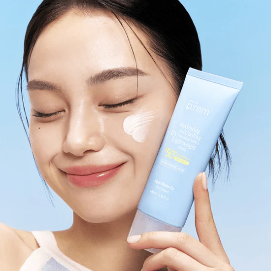 Woman applying MAKE P:REM Hyal Water Fit Sunscreen 100ml with a radiant smile, showcasing product texture and packaging.