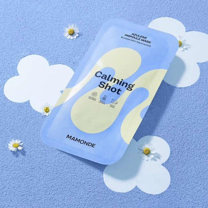 MAMONDE Calming Shot Azulene Ampoule Mask Pack on blue background with daisies, showcasing soothing skincare product packaging.