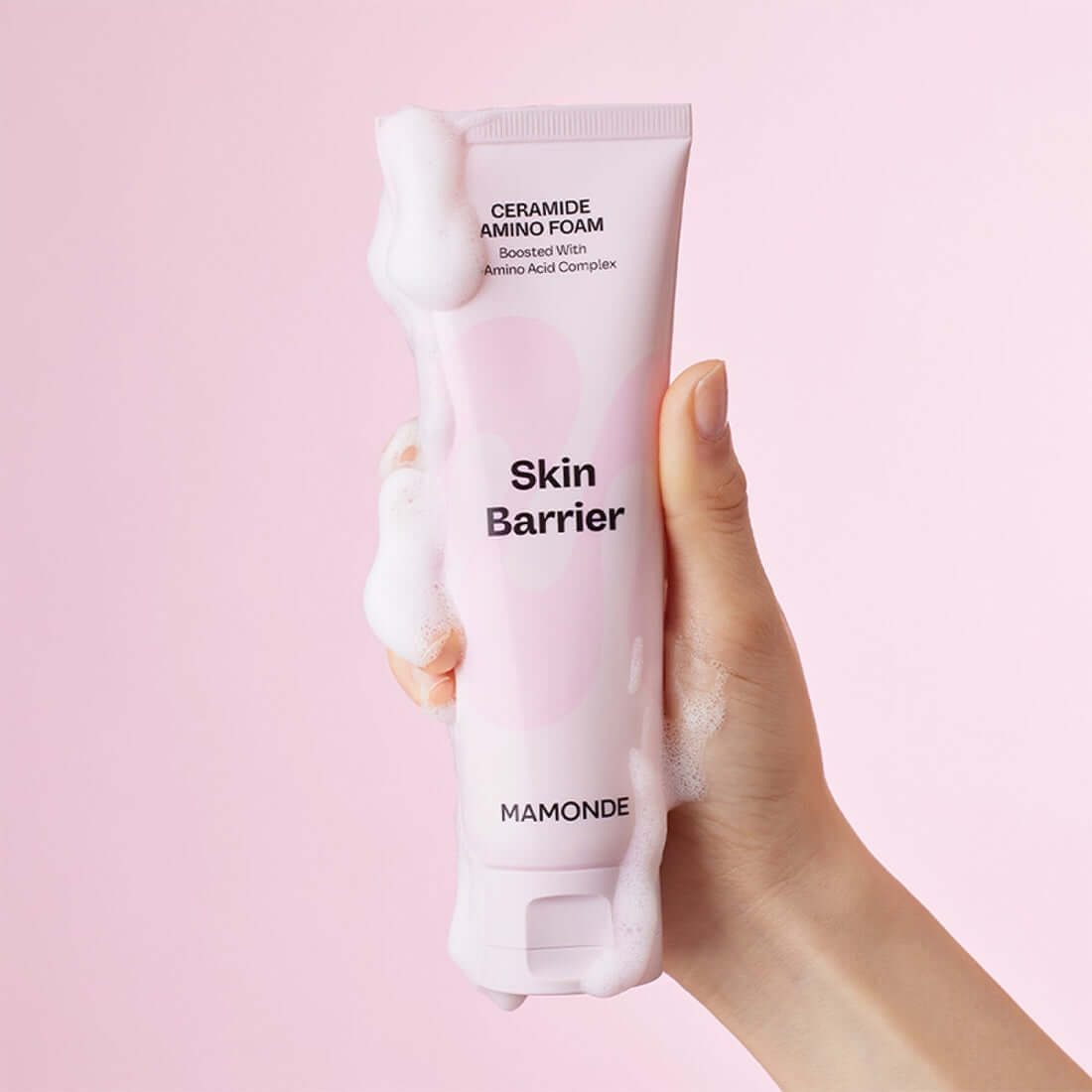 Hand holding MAMONDE Ceramide Amino Foam 120g with bubbles on pink background.