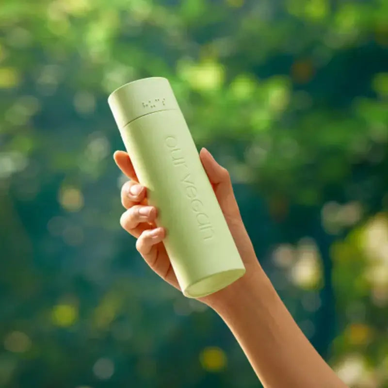 Person holding MANYO Our Vegan Heartleaf Moisture Soothing Toner 315ml against a green background