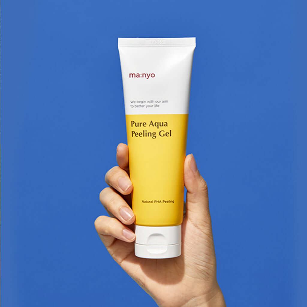 Hand holding MANYO Pure Aqua Peeling Gel 120ml against blue background